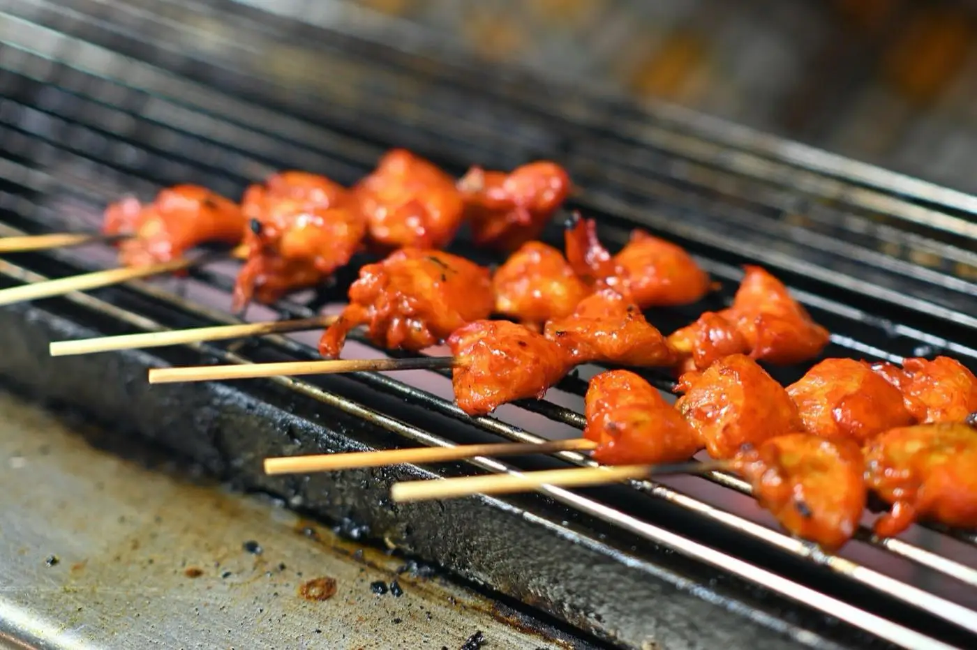 Marinated chicken skewers cooking over a charcoal grill